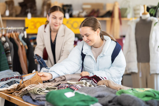 Woman with a teenage daughter chooses woolen warm pants near the counter in the sale area. Family shopping for winter clothes in the store