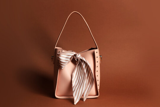 Stylish handkerchief and bag on brown background