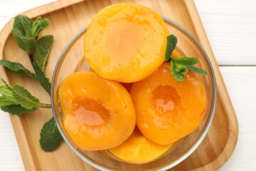 Pickled peaches and mint leaves in bowl on white wooden table, top view © New Africa