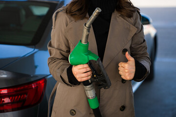 Woman holding gasoline nozzle and showing thumbs up © Rabizo Anatolii