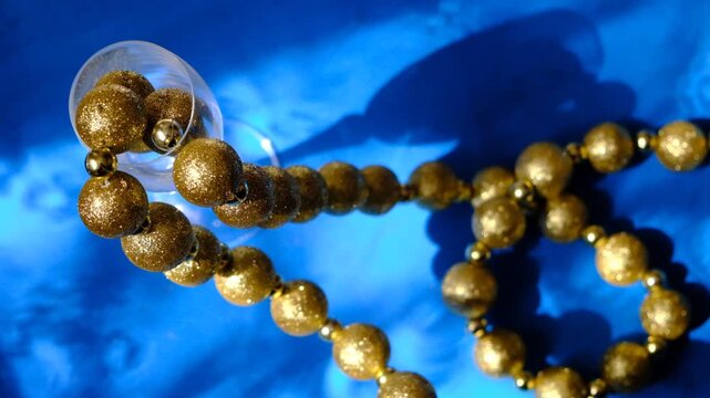 Champagne flute and glitter golden beads like luxury decor, high contrast, shadow and sunlight. Christmas creative layout with vintage decorations. Festive atmospheric mood