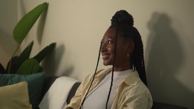 Smiling person with braided hair watching something interesting