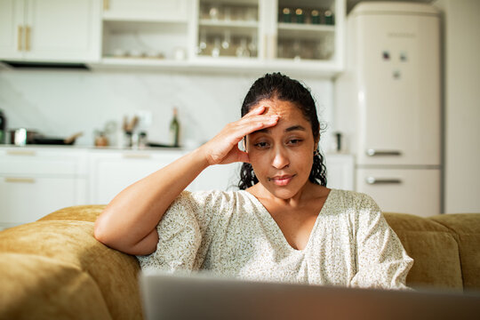Stressed woman looking at laptop in home kitchen
