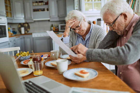 Senior couple reviewing bills at home kitchen table