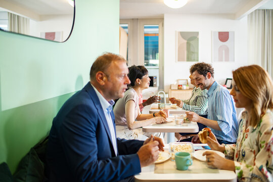 Coworkers eating lunch together in office cafeteria
