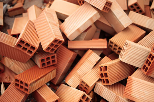 Close up of stacked hollow red clay bricks as construction material background, ceramic blocks for masonry, housing development, renovation, architecture, infrastructure, industrial building concept
