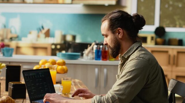 Software developer at home, writing code and debugging applications, IT engineering and command-line interfaces. Focused digital work with software maintenance on laptop in the kitchen.