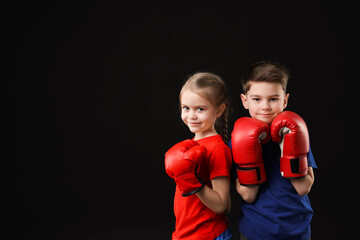 Fototapeta premium Cute kids in boxing gloves on black background, space for text