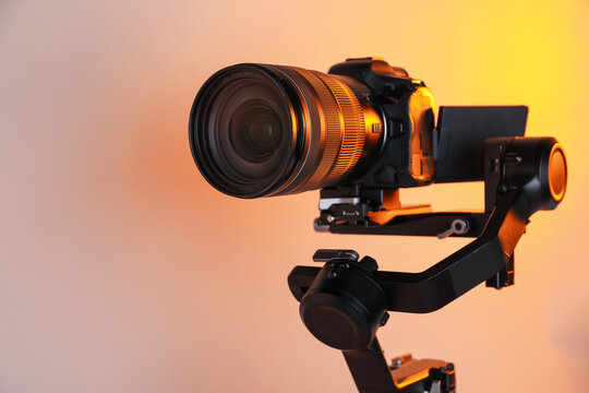Gimbal stabilizer with camera on color background, closeup. Space for text