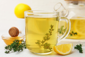 Obraz premium Fresh thyme tea in glass cup, honey and slice of lemon on grey table, closeup