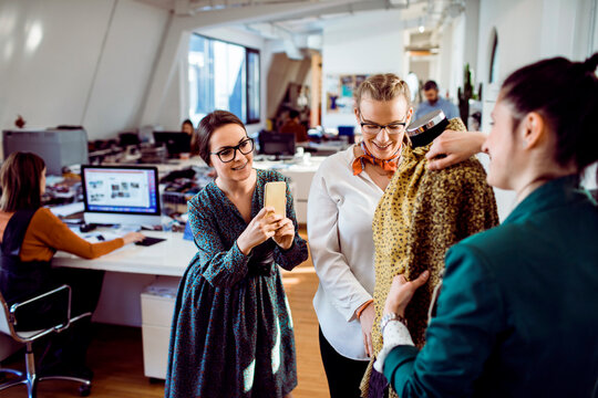 Fashion designers collaborating on dress in modern studio office