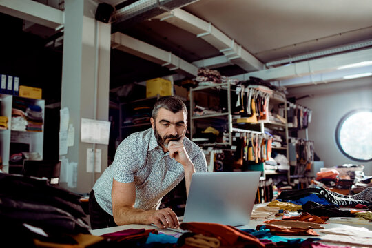 Small business owner using laptop in garment workshop