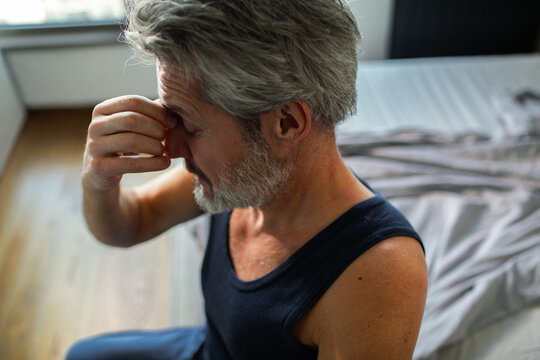 Middle-aged man with headache in bedroom at home