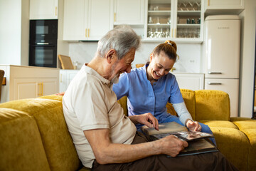 Obraz premium Caregiver and senior man looking through a photo album at home