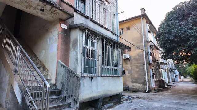 Gritty, functional architecture of a walk-up apartment building with weathered concrete walls. Aging housing infrastructure and decay of mid-century architecture in Chinese cities. Liuzhou, Guangxi