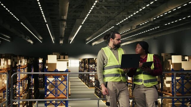 Warehouse teamwork showing two coworkers managing shipping operations in large scale distribution center. Facility supports e-commerce fulfillment and operational control, workforce. Copy space.