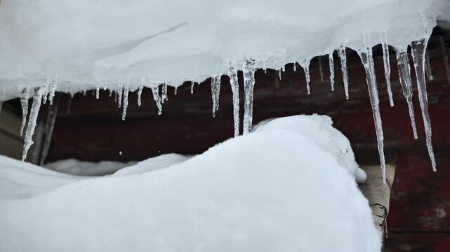 Icicles forming on a roof in winter, melting ice and snow dripping