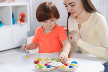 Obraz premium Mother and her son playing with toys on white table indoors