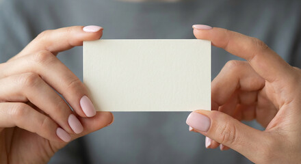 Obraz premium Female hands holding blank white business card for mockup, perfect for corporate identity concepts, contact information or branding presentation designs