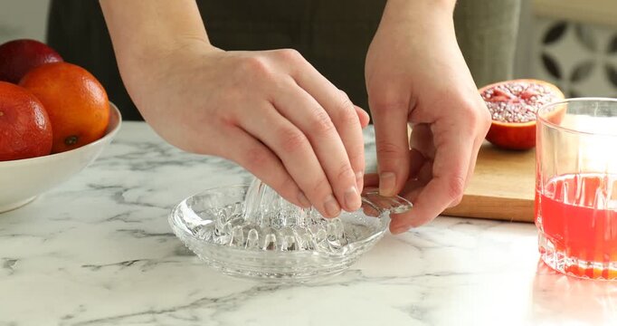 Making juice. Woman with Sicilian orange using juicer at white marble table, closeup
