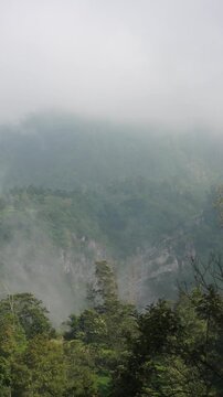 Atmospheric mountain landscape featuring steep cliffs partially covered by moving fog