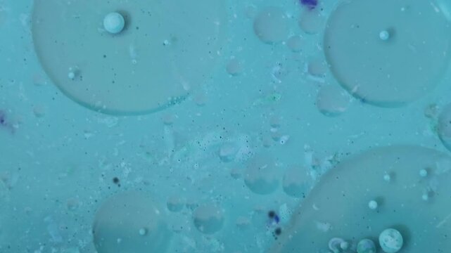 Una toma de cerca de varias burbujas de agua y aceite en movimiento en un fondo de color azul