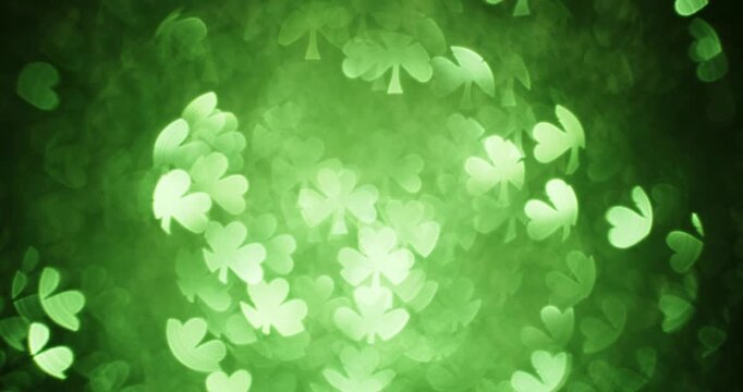 Soft glittering lights in the shape of a three leaf clover. Shining bokeh particles in a shamrock shape sparkling and glowing for a shimmering green St Patricks Day background. Seamless Loop.