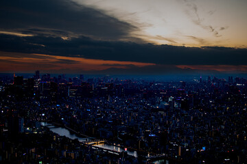 Fototapeta premium Cinematic Tokyo skyline at dusk with Mount Fuji silhouette under a dramatic sunset sky