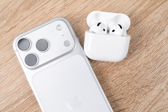 Bar, Montenegro: February 6, 2026: Iphone 17 pro with triple camera next to open white wireless AirPods earbuds case on a wooden surface, modern electronics, portability everyday tech essentials today