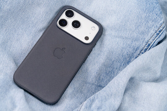 Bar, Montenegro: February 6, 2026: Close up of Apple 17 pro back triple camera module lying light blue denim fabric, textured protective case soft folds forming casual technology lifestyle background