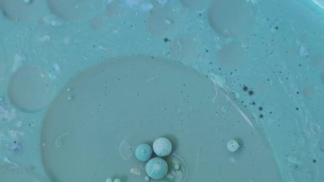 Una toma de cerca de varias burbujas de agua y aceite en movimiento en un fondo de color azul
