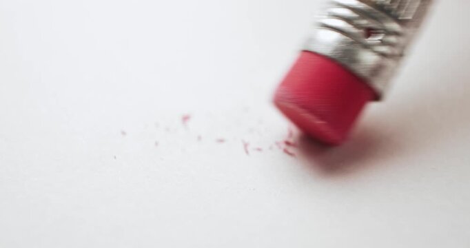 Closeup of pink pencil eraser erasing and creating a mess on white paper. Conceptual bad idea, fixing problems, failure or mistake, wrong decision, or to remove an error. Back to School supplies.