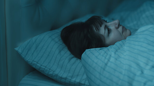 Woman lying awake in bed at night with insomnia, have fun and enjoy