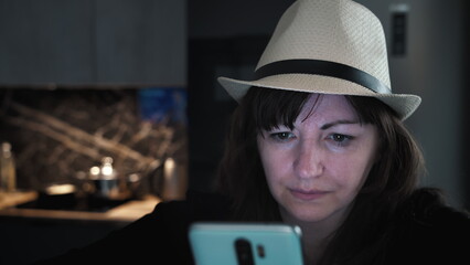 Woman wearing hat looking at smartphone indoors