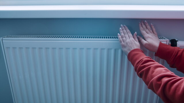 heating problems, woman making the battery temperature more trying to keep warm in winter, heat supply to the batteries at home does not work