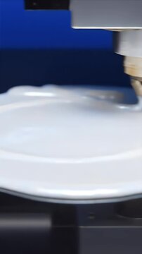 Close up CGI depiction of an incremental layering technique with a white material being deposited on a circular base against a deep blue background with studio lighting