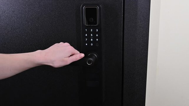 A woman opens a modern smart door lock with a digital keypad using a code.