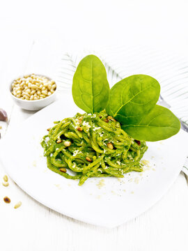 Spaghetti with spinach and nuts in plate on white board