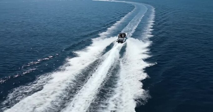 A speedboat racing across the vibrant blue ocean, leaving a frothy wake under a clear sky