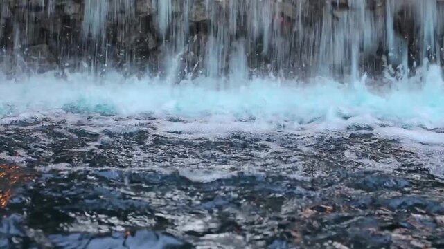 Close-up of a cascading waterfall with foamy water and dark rocks
