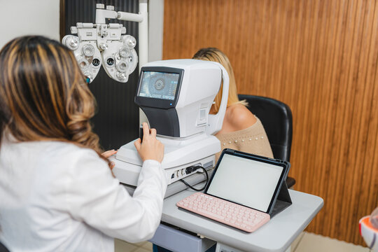 Optometrist examining patient eyes with autorefractometer in clinic