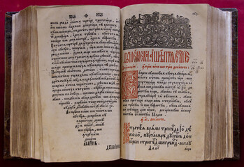 An antique Gospel book, likely printed in the 17th or 18th century, featuring ornate Cyrillic text and detailed woodcut engravings, at the Saambata de Sus monastery - Romania