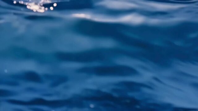 Calm and rhythmic ocean waves gently undulating on the water surface, showing the deep blue colors of the sea and natural movement.