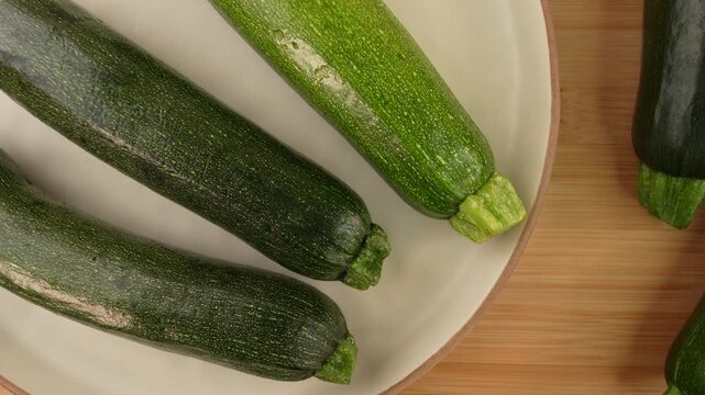 Fresh green zucchini in a plate on wooden background.