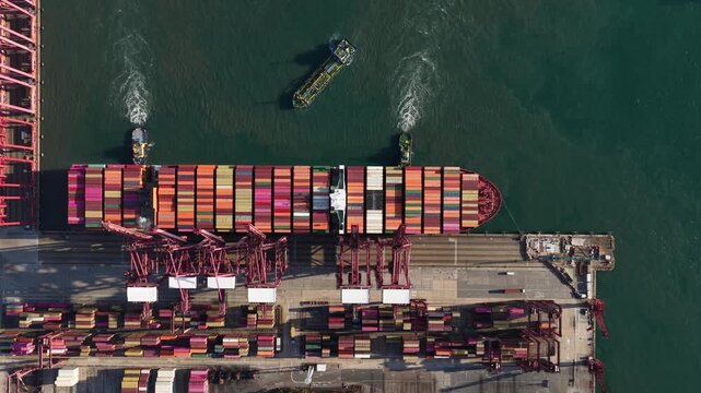 Aerial top view of a container ship docking at a port terminal