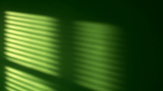 Blurry green light shines through window blinds indoors at night