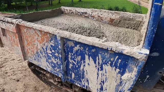 Tracked dumper transporting fresh concrete across a construction site. Compact construction machine hauling concrete for foundation or structural work.