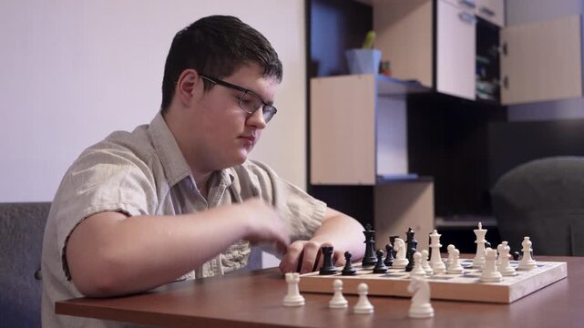 Teenage boy plays chess at home at the table. The concept of children development.