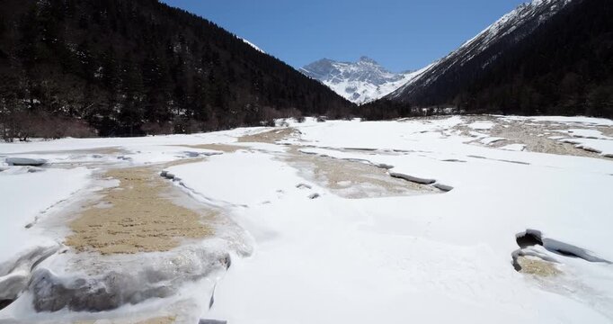 Camera at pavilion moving to show snow covered travertine pools and terraces in famous Huanglong scenic area, World Heritage site located in China's beautiful Sichuan province.