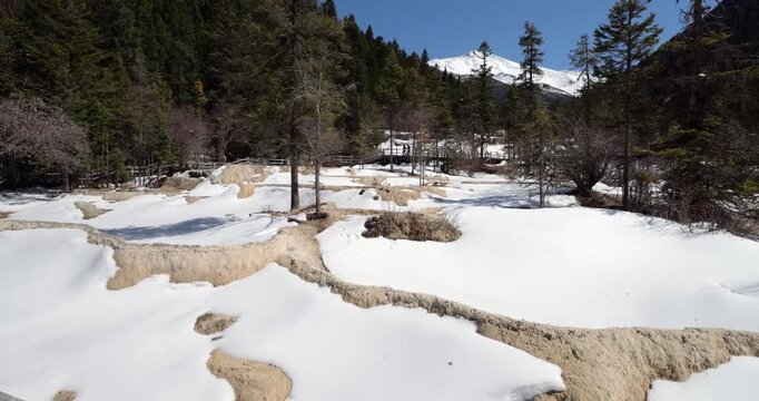 Beautiful view of travertine terraces covered in snow at Huanglong scenic area, World Heritage Site located in Sichuan province of China. Low season at end of March with still impressive views